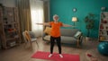 An elderly woman does a warmup before training. The greyhaired woman raises her arms above her head and reaches up