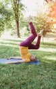 An elderly woman does yoga in the park on the grass, lifting her legs high up Royalty Free Stock Photo