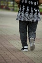 An elderly woman dressed in black running-in the park.