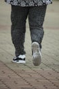 An elderly woman dressed in black running-in the park.