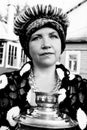 An elderly woman dressed in the old Russian style with a samovar, a bright headscarf on her shoulders and a bunch of bagels Royalty Free Stock Photo