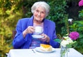 Elderly Woman Drinking Coffee at the Garden Table Royalty Free Stock Photo