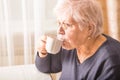 Elderly woman drinking hot drink at home. Senior pensioner female holding cup of coffee in their hands