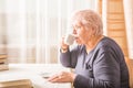 Elderly woman drinking hot drink at home. Senior pensioner female holding cup of coffee in their hands