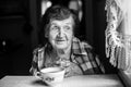 Elderly woman, drinking tea sitting at the table in the house. Royalty Free Stock Photo