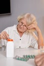 elderly woman with drugs in hands reading prescription of medication, sitting alone at home Royalty Free Stock Photo