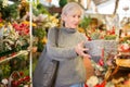 Elderly woman in festive mood choosing Christmas decorations in store Royalty Free Stock Photo