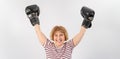 An elderly woman in fighting gloves raises her hands up on a white background. Victory in a duel