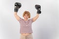 An elderly woman in fighting gloves raises her hands up on a white background. Victory in a duel