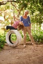 Elderly woman, garden and grandchild playing with grandma or holidays and having fun on a tyre swing in summer. Excited Royalty Free Stock Photo
