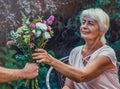 Elderly woman get a beautiful bouquet of field flowers. Royalty Free Stock Photo