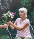 Elderly woman get a beautiful bouquet of field flowers. Royalty Free Stock Photo