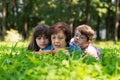 Elderly woman, girl and boy are lying on the lawn and reading a book against green nature background.Grandmother and grandchildren