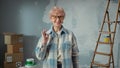 Elderly woman in glasses is looking at camera, showing ok gesture and smiling. Portrait of female pensioner in blue Royalty Free Stock Photo