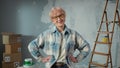 Elderly woman in glasses is looking at camera and smiling. Portrait of female pensioner in blue plaid shirt is posing in Royalty Free Stock Photo