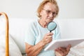 Elderly woman with glasses and loupe using a digital tablet Royalty Free Stock Photo