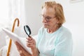 Elderly woman with glasses and loupe using a digital tablet Royalty Free Stock Photo