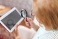 Elderly woman with glasses and loupe using a digital tablet Royalty Free Stock Photo