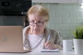 Elderly woman in glasses working using laptop at home, looking on computer Royalty Free Stock Photo