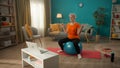 Elderly woman goes in for sports sitting on a fitness ball in front of a laptop. An elderly woman sits on a fitball with Royalty Free Stock Photo