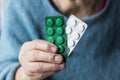 An elderly woman, a grandmother, holds medicines, pills, drugs in her hand close-up