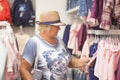 Elderly woman choosing baby clothes in the shop. Royalty Free Stock Photo