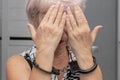 An elderly woman in handcuffs hides her face on a blurry background. Elderly criminal, criminal liability of pensioners, domestic