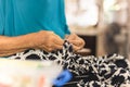 Elderly woman hands using needle and thread to mend a dress.