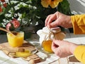 An elderly woman is hands wrap a glass jar of rustic natural flower honey. Honey and a cup of green tea on a background of flowers Royalty Free Stock Photo