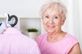 Elderly woman hanging shirt on hanger