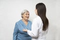 An elderly woman has a cute conversation with a young doctor. They are happy to see each other and smile. Royalty Free Stock Photo