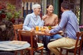 Elderly woman  having conversation with young adult female and her boyfriend, smiling, having breakfast together in outdoor cafe Royalty Free Stock Photo