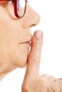 Elderly woman is having finger on her lips. Profile. Royalty Free Stock Photo