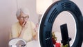 Elderly woman having a video call while applying make up and getting ready for valentines day date Royalty Free Stock Photo