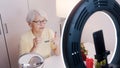 Elderly woman having a video call while applying make up and getting ready for valentines day date Royalty Free Stock Photo