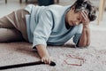 Woman with headache lying on the floor with walking stick after attack Royalty Free Stock Photo