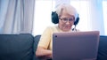 Elderly woman with headset having video call with family and waving to camera. Old people and technology