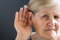 Elderly woman with hearing loss on grey background. Age related