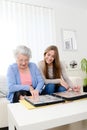 Elderly woman with her young granddaughter at home looking at memory in family photo album Royalty Free Stock Photo