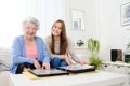 Elderly woman with her young granddaughter at home looking at memory in family photo album Royalty Free Stock Photo