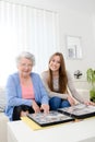 Elderly woman with her young granddaughter at home looking at memory in family photo album Royalty Free Stock Photo