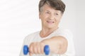 Elderly woman holding blue dumbbell