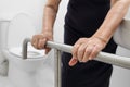 Elderly woman holding on handrail in toilet. Royalty Free Stock Photo