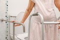 Elderly woman holding on handrail in toilet. Royalty Free Stock Photo