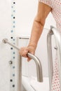 Elderly woman holding on handrail in toilet. Royalty Free Stock Photo