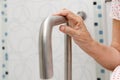 Elderly woman holding on handrail in toilet. Royalty Free Stock Photo