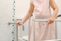 Elderly woman holding on handrail in toilet. Royalty Free Stock Photo