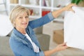 elderly woman holding paint roller for wallpaper