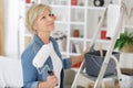 elderly woman holding paint roller for wallpaper