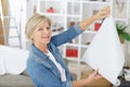 elderly woman holding paper roller for wallpaper redecoration